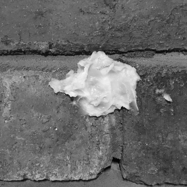 a glob of Vaseline nestles between the bricks of an exposed wall